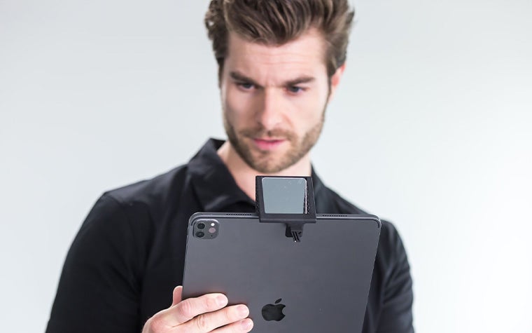 A man holding an iPad featuring the SAM Mirror attachment.