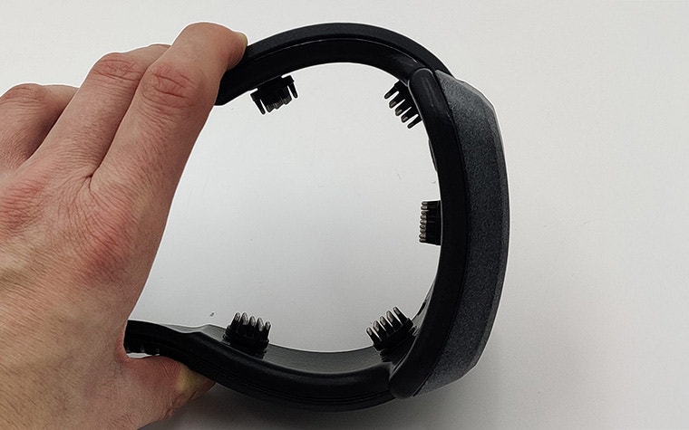 A hand squeezing the NeuroPlay EEG headset together, displaying its flexibility and strength.