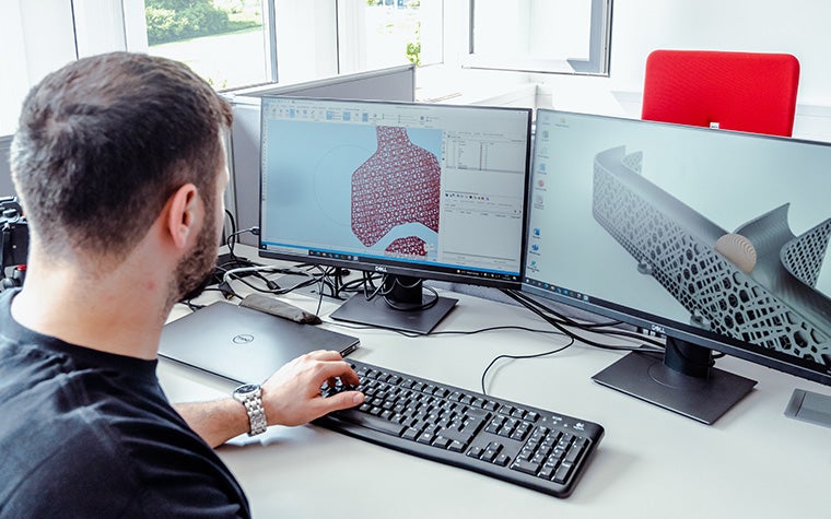 Materialise Magicsを使って2台のデスクトップ・コンピュータの画面を見る男性