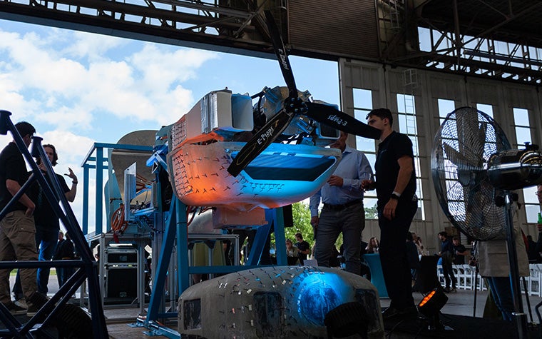A group of students from TU Delft standing in an aircraft hangar next to a partially disassembled Sling 4 kit aircraft that they have retrofitted with a liquid hydrogen engine.