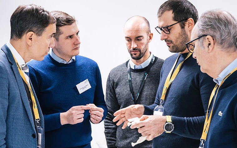 A group of CMF Dry Bone Experience attendees in a discussion. One of the men holds a dry bone.