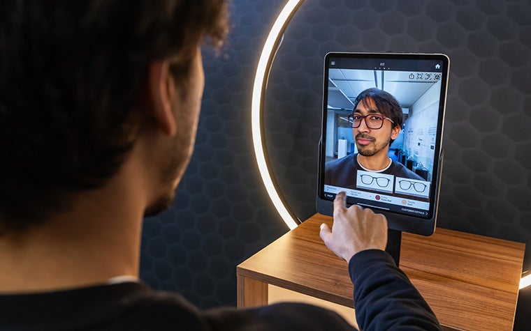 A man uses the Eyewear Fitting Suite on an iPad. The screen shows his face, along with a generated image of 3D-printed eyewear.