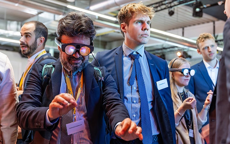 People at a conference wearing AR glasses and testing out new functionalities of Materialise software.