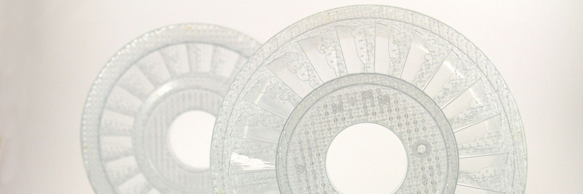 Two transparent, disc-shaped plastic molds in front of a white background