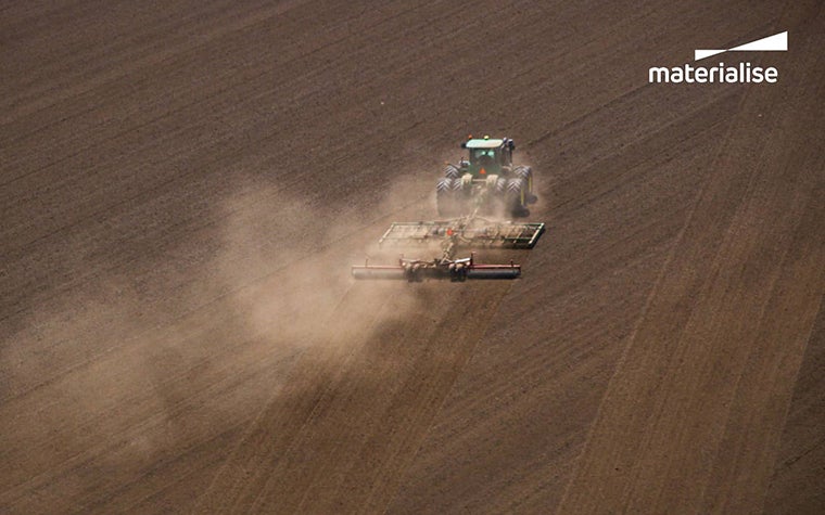 A farm machine crosses a dusty field
