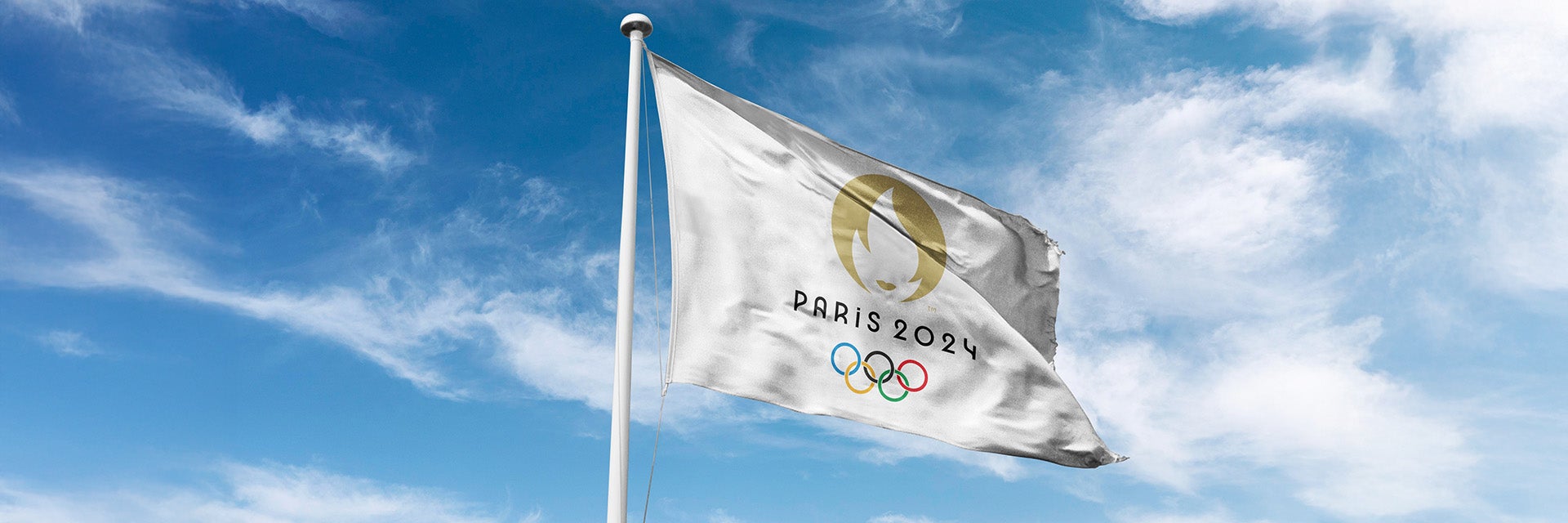 A picture of the Paris 2024 Olympic flag blowing in the wind with the sky in the background