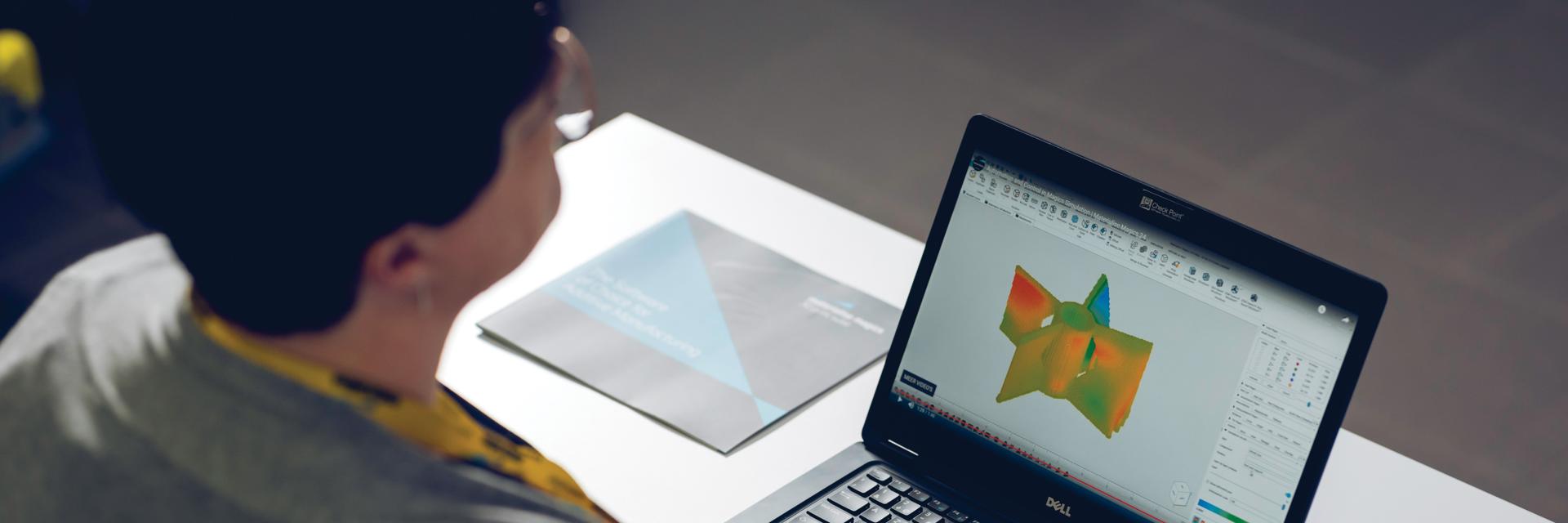 Woman using Magics on a laptop next to an informational brochure