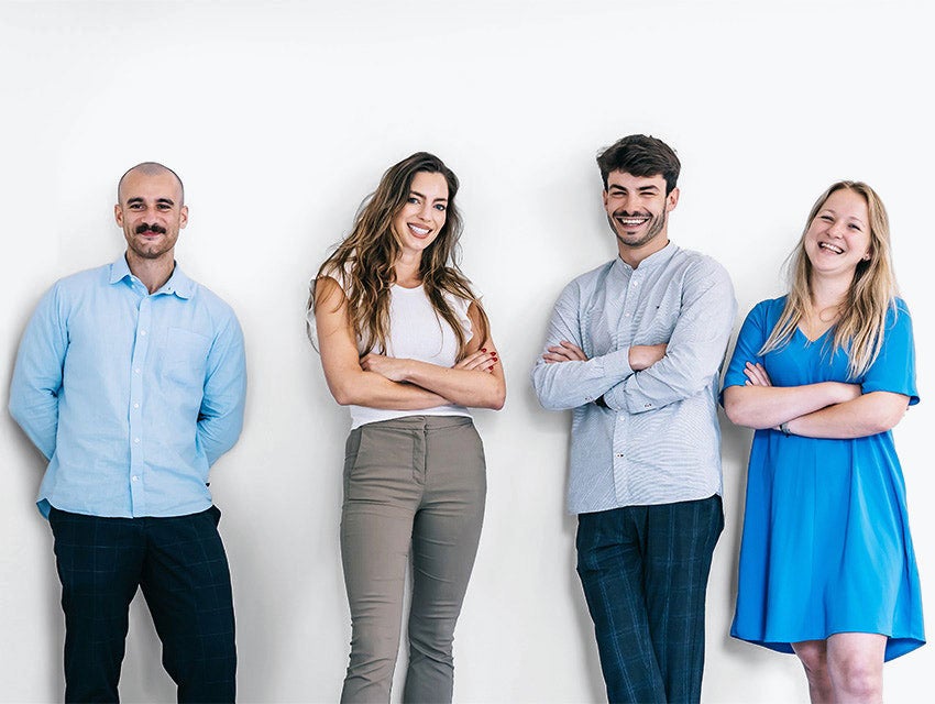 Group of four professionals stannding next to each other and smiling while looking into the camera