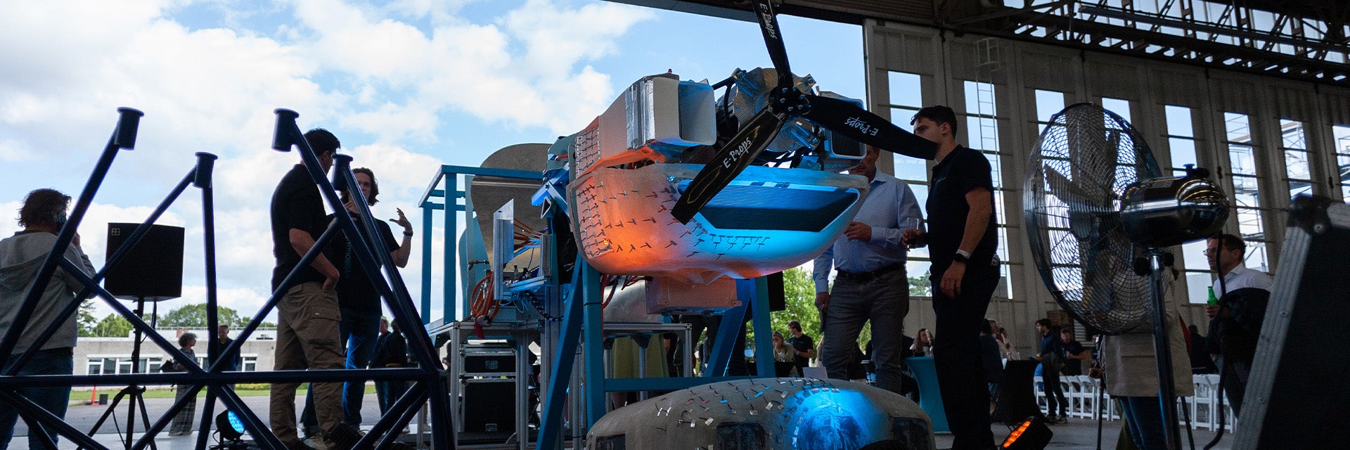 A group of students from TU Delft standing in an aircraft hangar next to a partially disassembled Sling 4 kit aircraft that they have retrofitted with a liquid hydrogen engine.