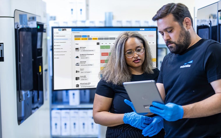 Two Materialise employees discuss a project on a small tablet.