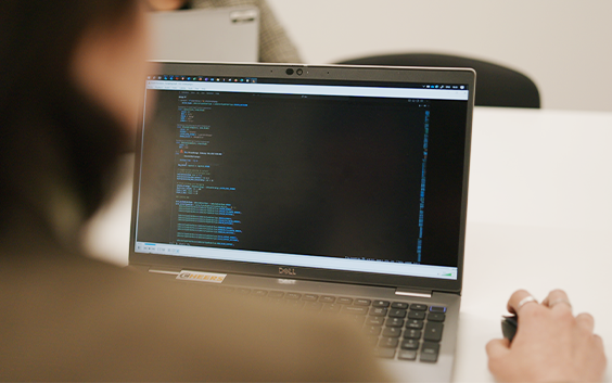 A laptop screen with coding, viewed from over the shoulder of the coder