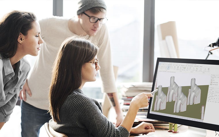 Three colleagues reviewing the preparation for 3D-printed part in Magics software on a computer screen