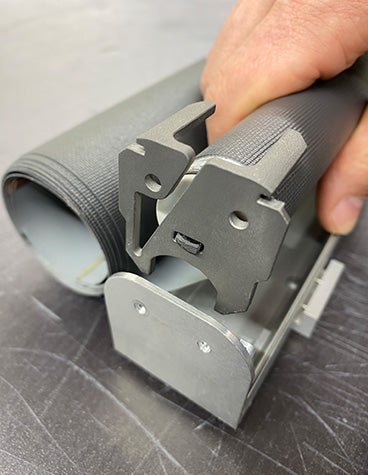 A hand holds a roller coupler featuring Lufthansa's metal 3D-printed titanium latch.