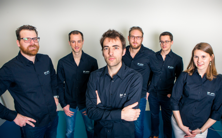 A group of men and women wearing phits orthotics uniforms standing against a white wall.