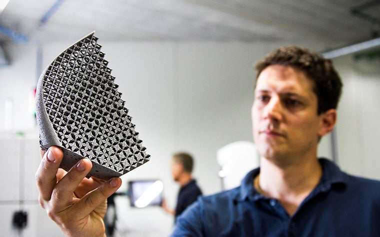 A man holding a 3D-printed part and assessing the quality