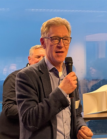 Henri Werij, Dean of the Faculty of Aerospace Engineering TU Delft, speaking into a microphone at the opening of Materialise's Aerospace Competence Center