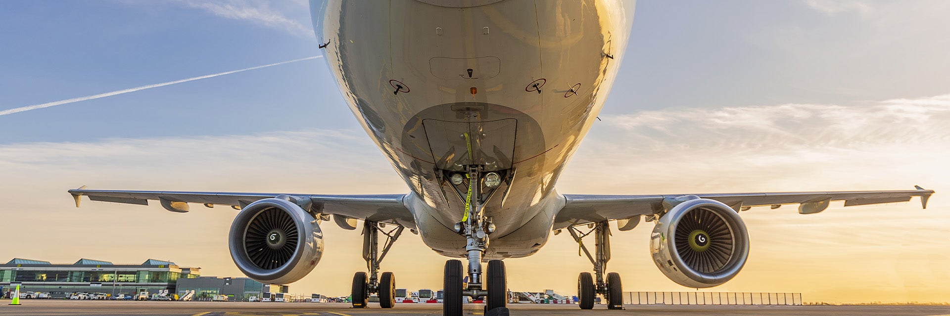 Die Nase eines großen Verkehrsflugzeugs auf einer Landebahn mit einem Sonnenuntergang im Hintergrund.