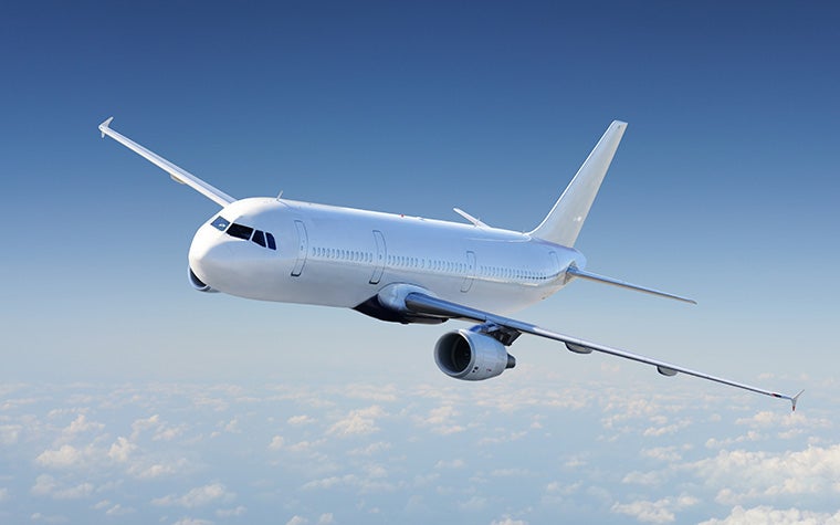 An unbranded commercial airplane flying against a blue sky with intermittent clouds.