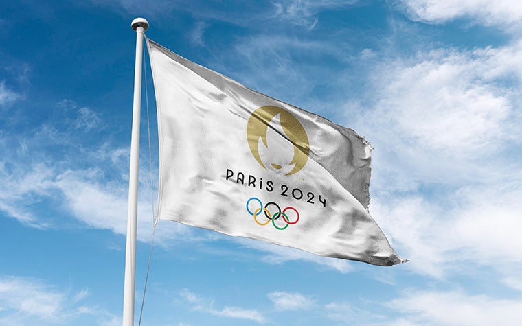 A picture of the Paris 2024 Olympic flag blowing in the wind with the sky in the background
