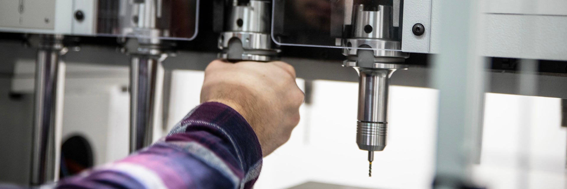 A hand adjusting a tool on equipment