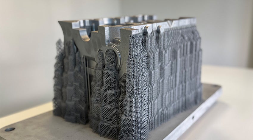 A metal 3D-printed crankcase produced by the BÖLLINGER GROUP sitting on a wooden table.