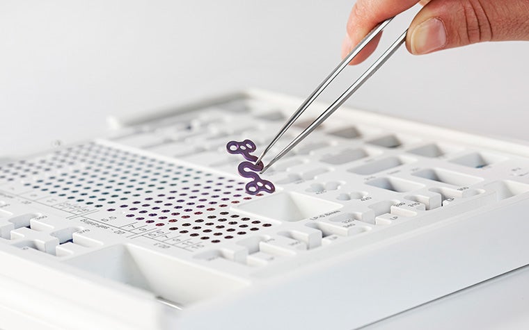 Tweezers pulling the S-plate out of the Orthognathics module, including various screws