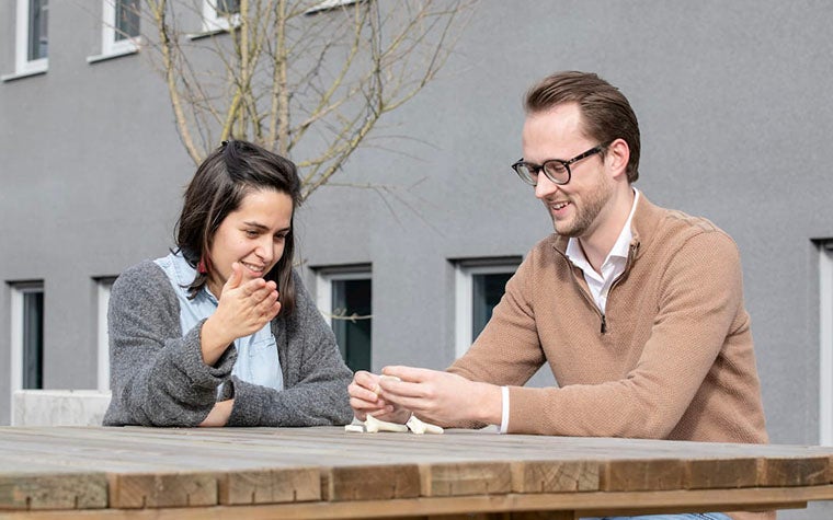 Two colleagues looking at 3D-printed surgical guides outside at a picnic table