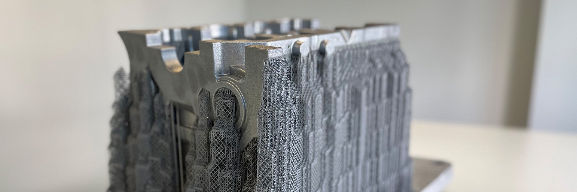 A metal 3D-printed crankcase produced by the BÖLLINGER GROUP sitting on a wooden table.