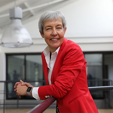 Brigite de Vet-Veithen smiling while leaning on a railing in the Materialise office
