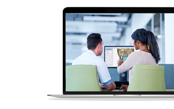 A man and a woman looking at a computer screen to plan for CMF preoperative planning.