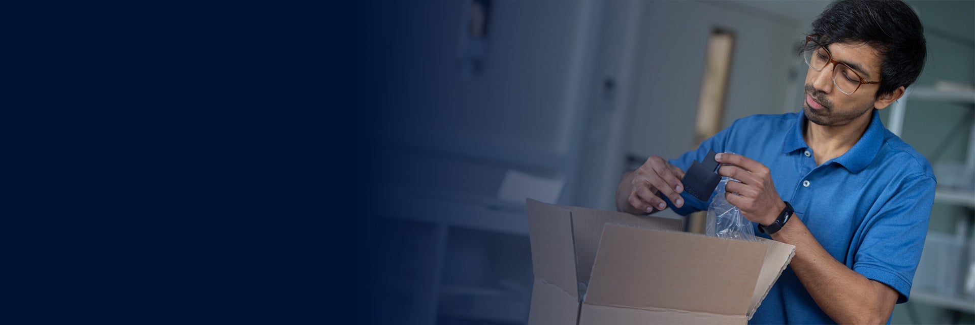 A man unboxes a small, black, 3D-printed part.