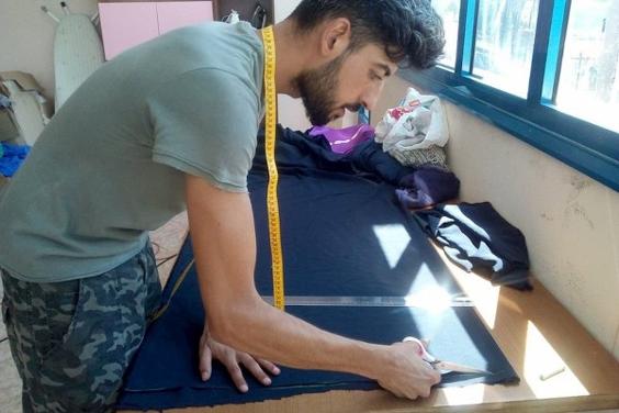 Man cutting fabric with measuring tape around his neck