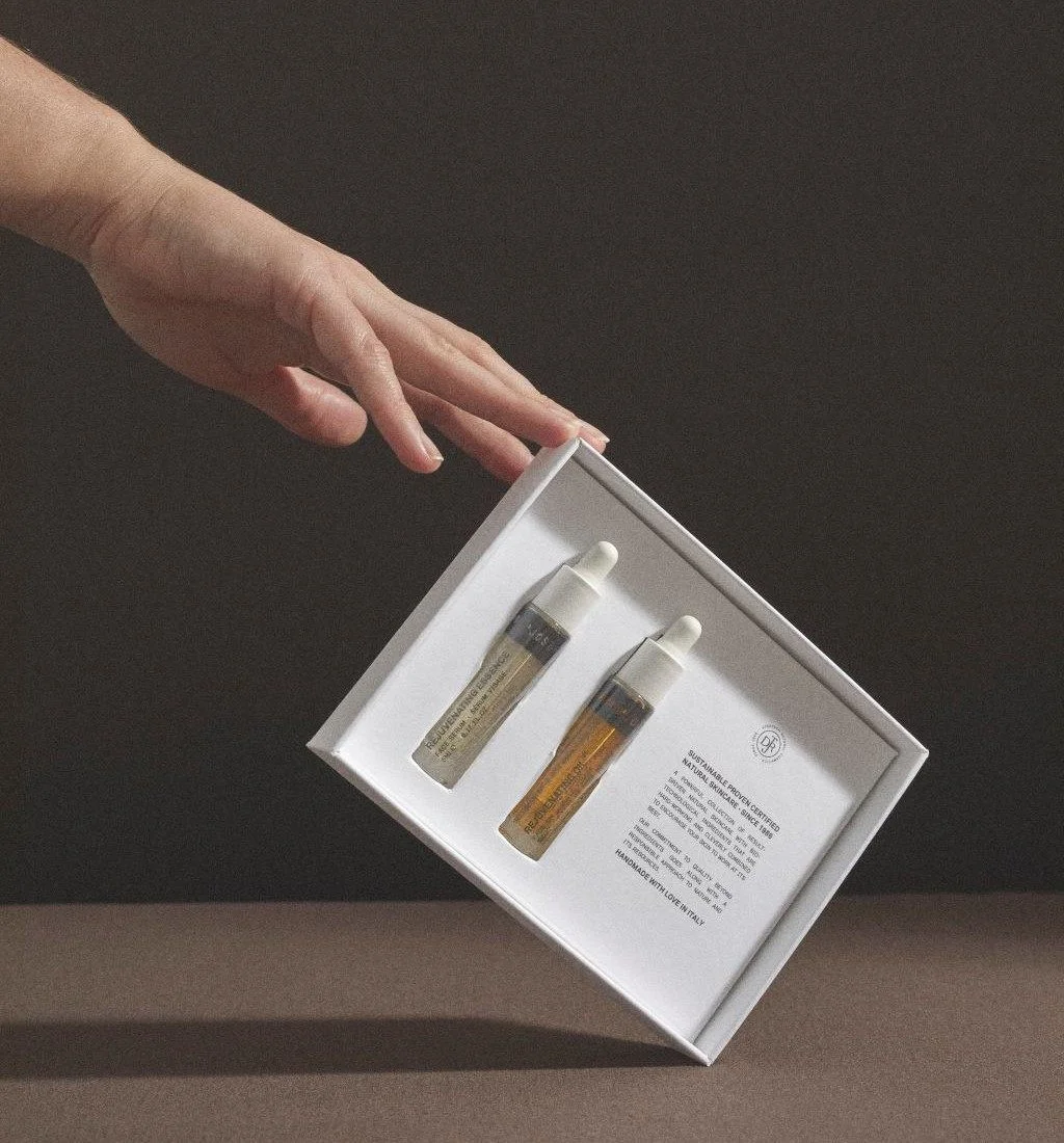 A hand holding a box with two small bottles