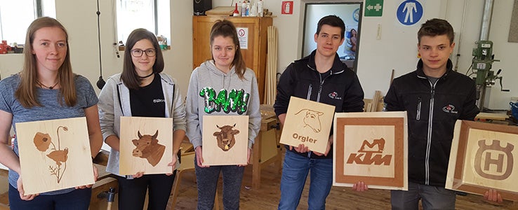 Schülerinnen und Schüler halten ihre Abschlusswerke in die Kamera