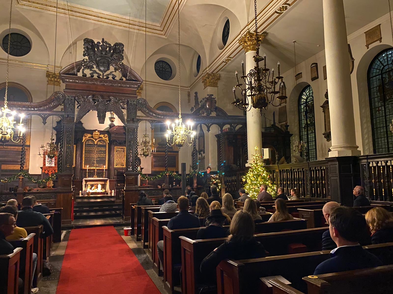 Congreation sitting inthe pews of St Margaret's. The Nativity can bee seen in front of the altar.