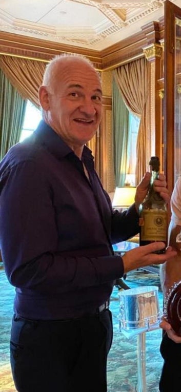 Zac smiling at camera holding a bottle of wine. 