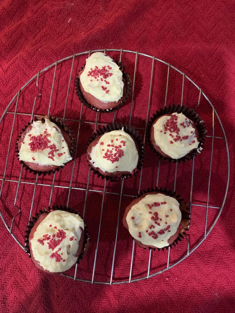 Six iced cup cakes sitting on a metal cooling tray