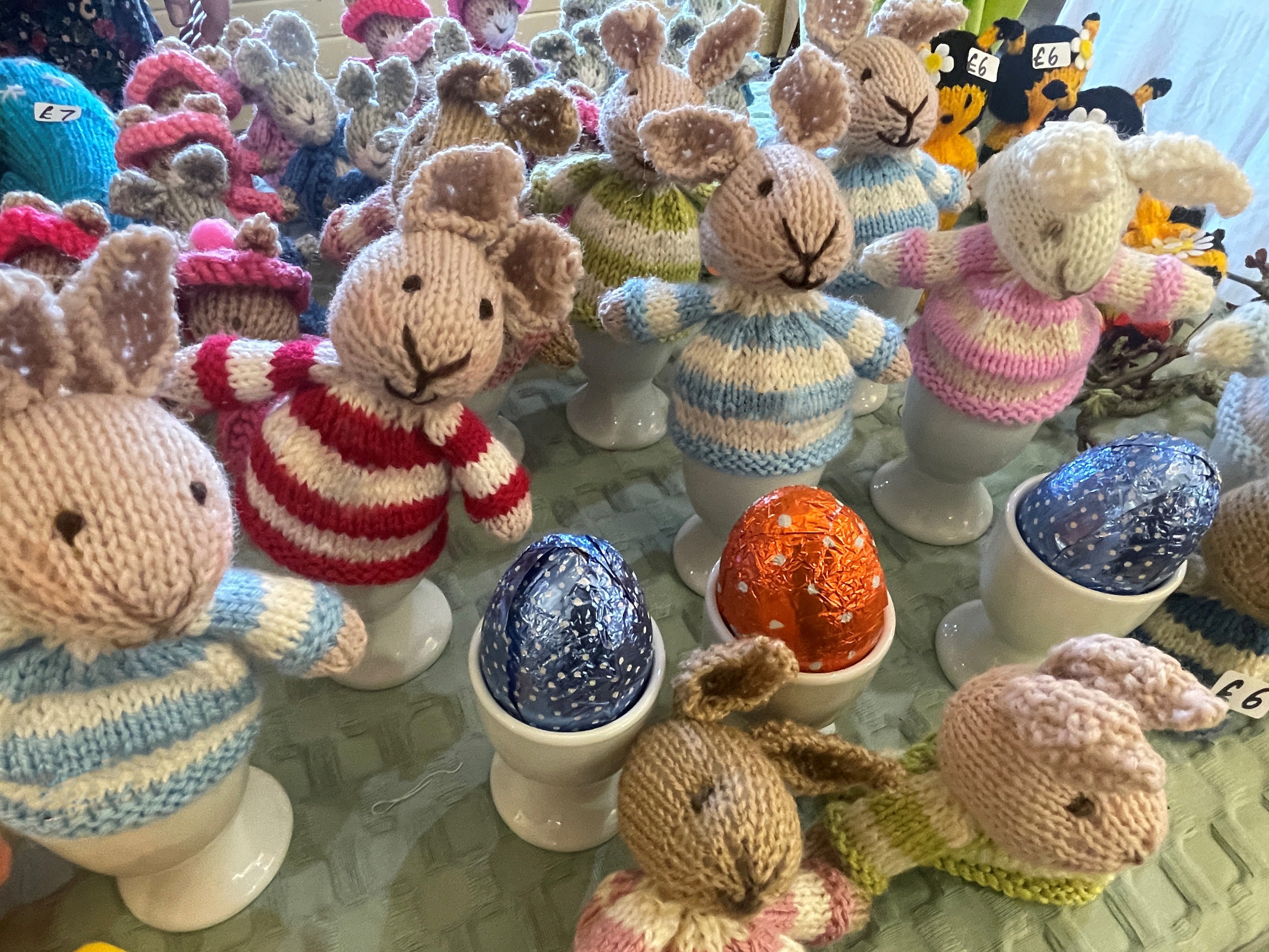 Easter bunnies in stripy jumpers egg cup covers and foild covered chocolate eggs.