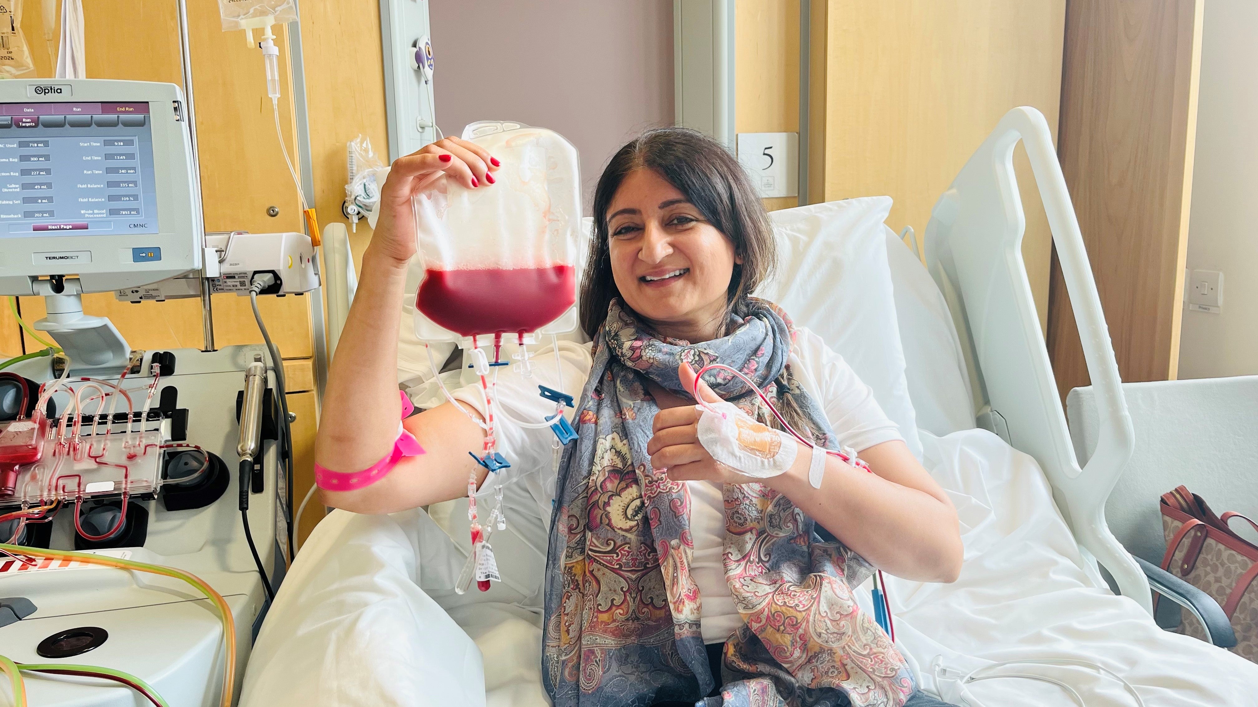 Asian stem cell donor smiling and holding a bag of stem cells