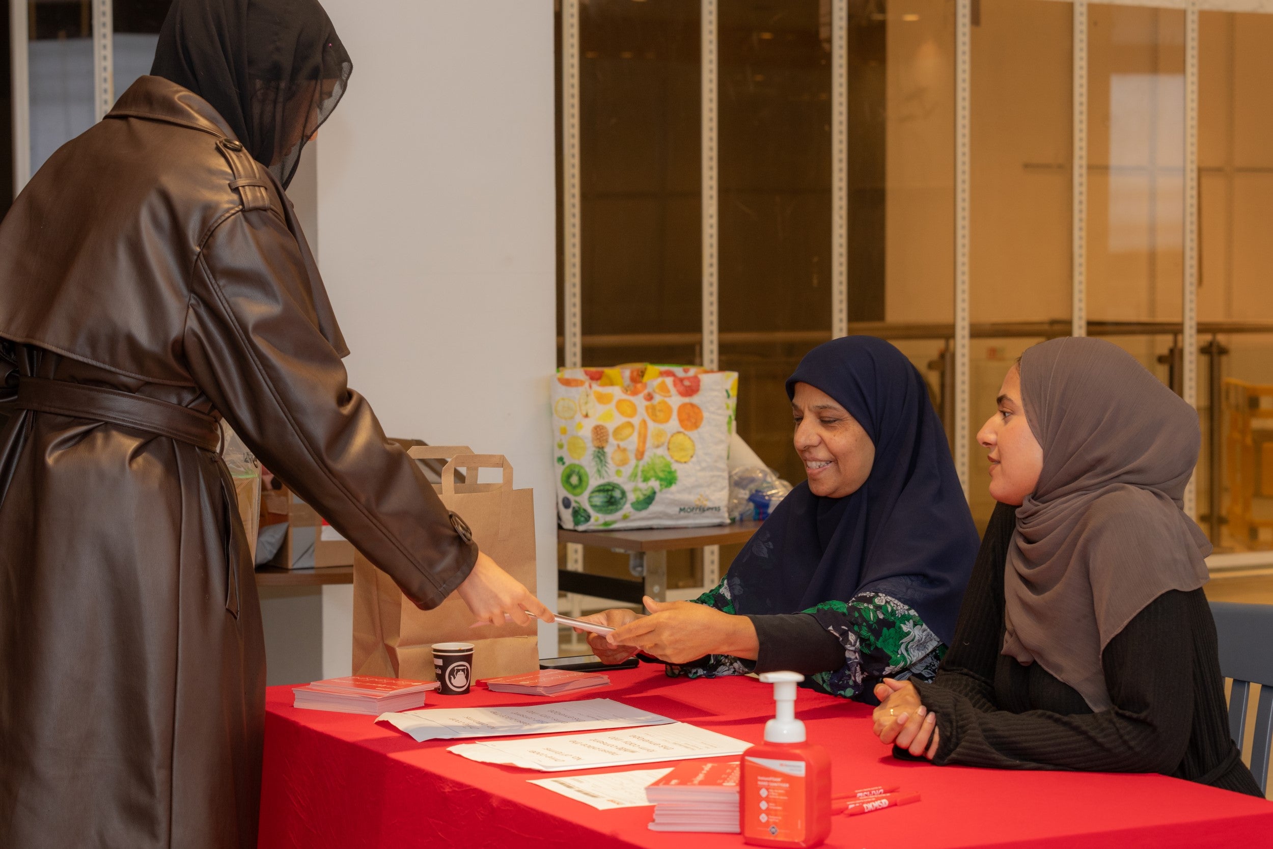 Three women at a DKMS registration stand 