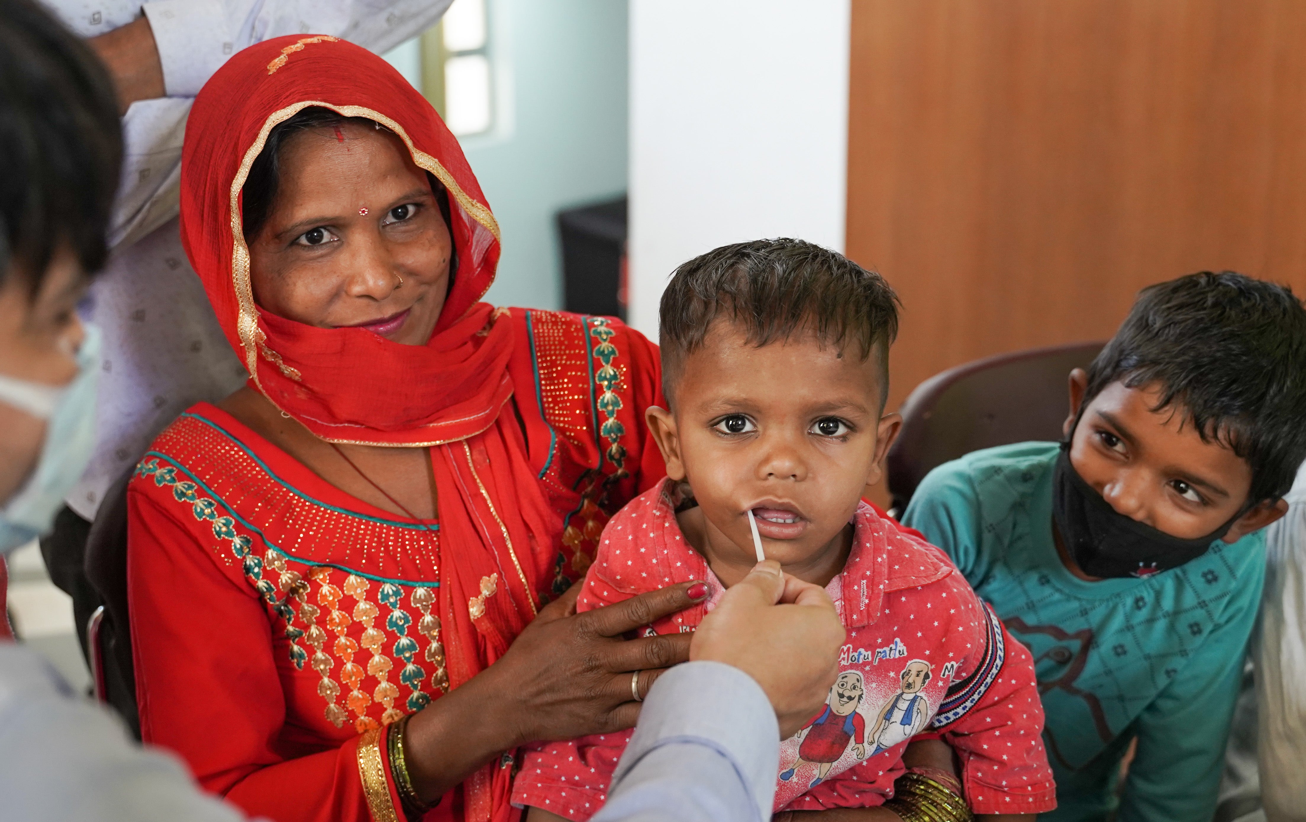 Indian lady with her two sons - one son is being swabbed