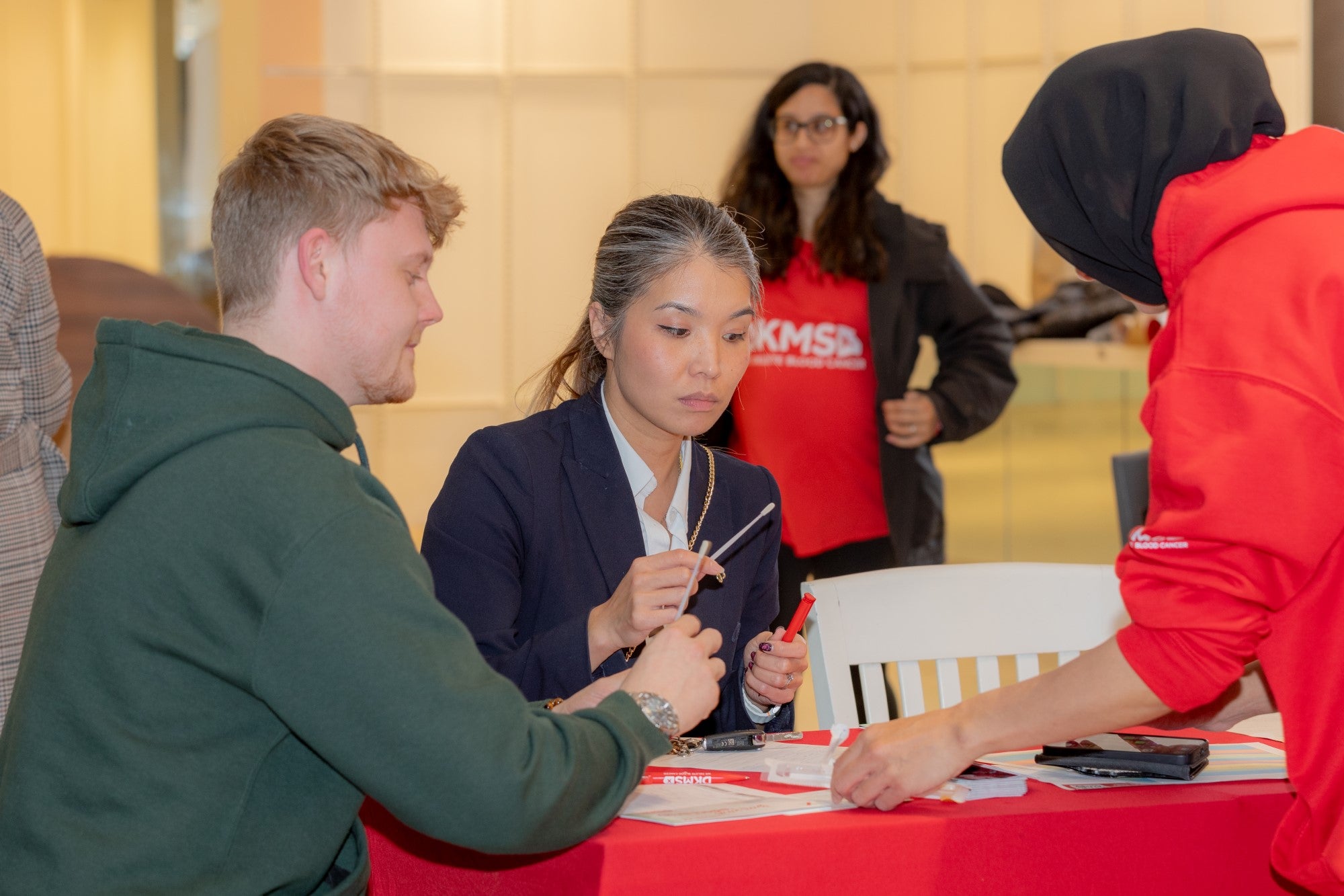 A white man and Asian woman registering at a DKMS event