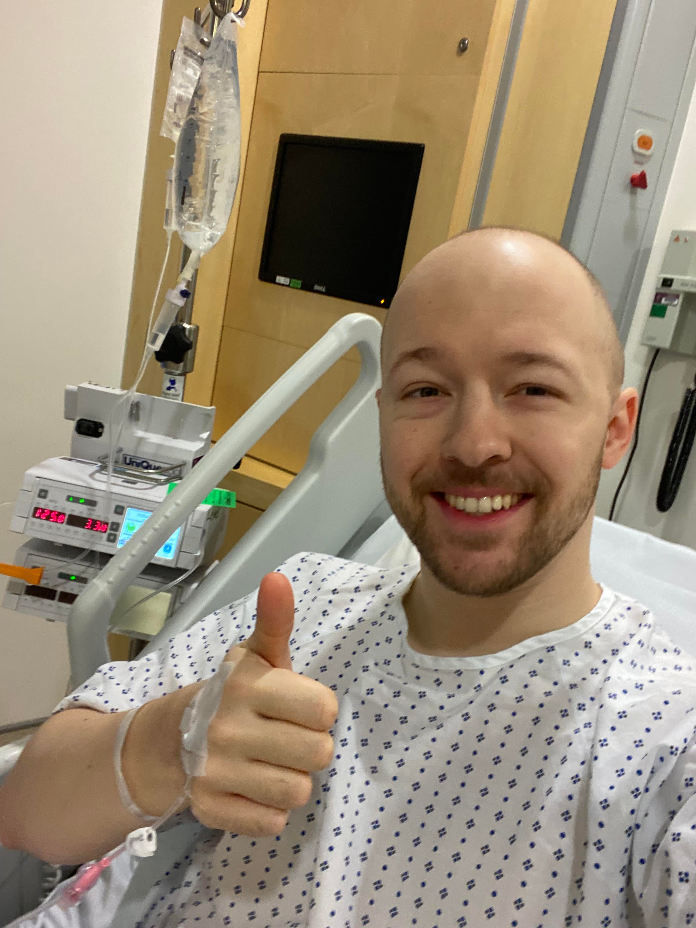 Ethan in a hospital bed giving a thumbs up