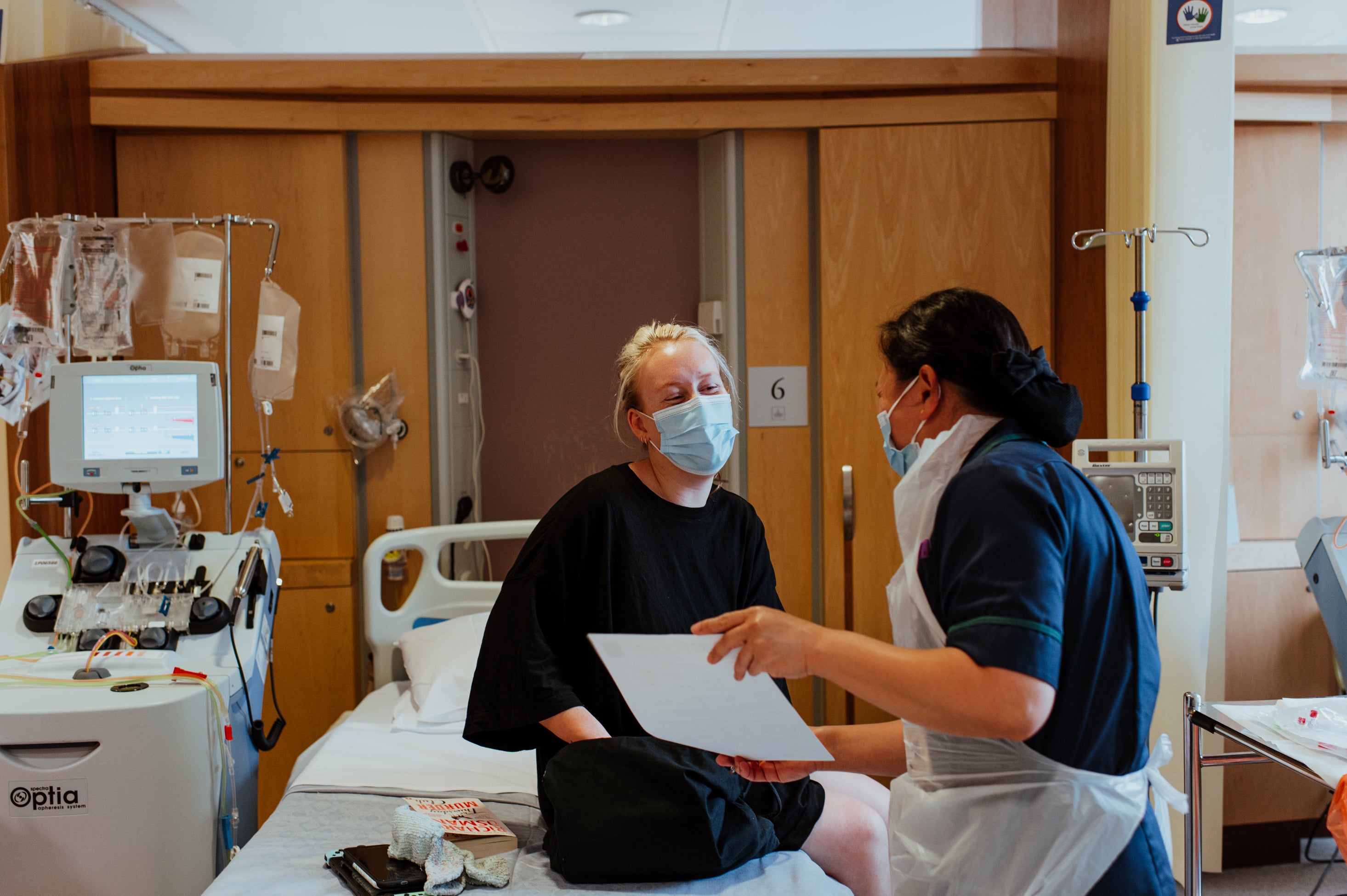 A donor sat on a hospital bed with a nurse showing them a form