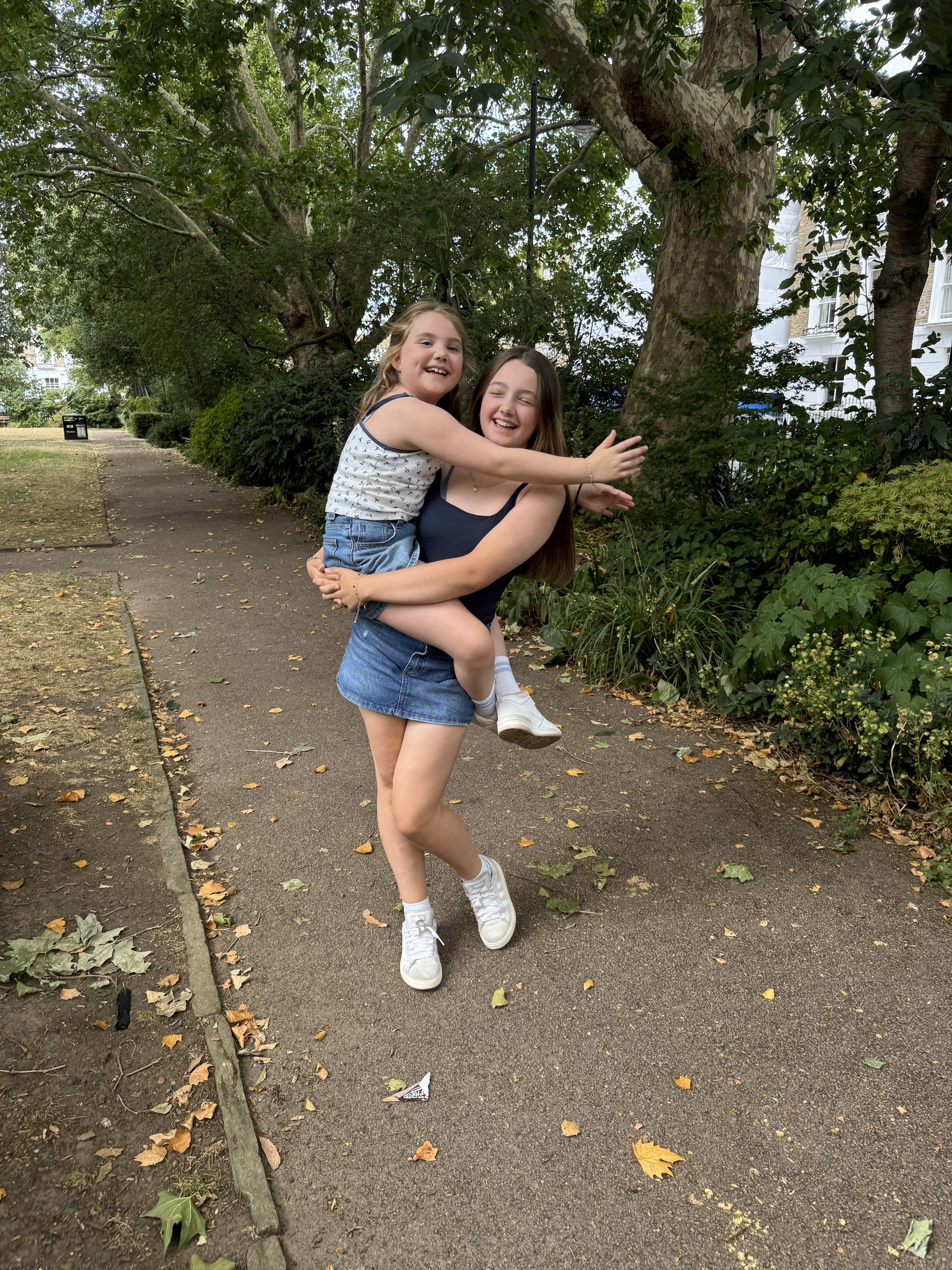 Patient Emilia's big sister Ellie holds her in her arms in the park on the morning Emilia gets to meet the stem cell donor who saved her life