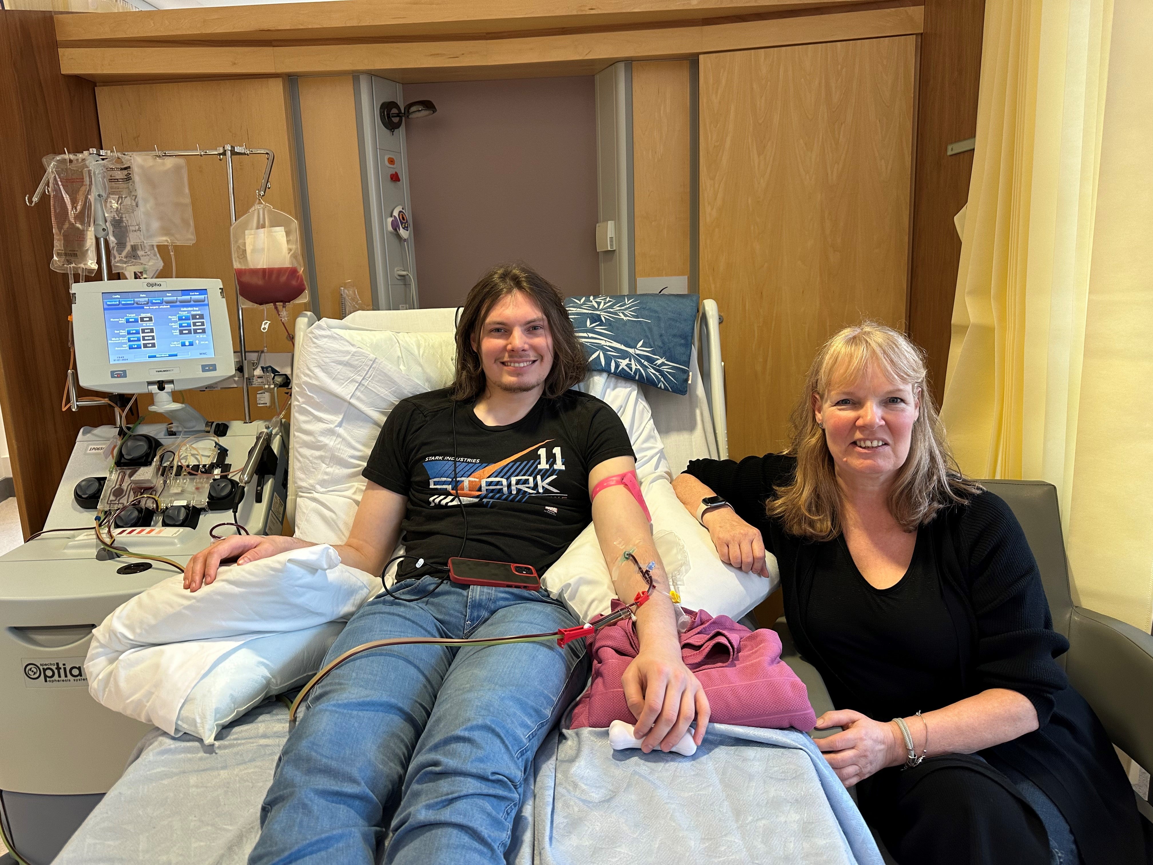 Son lying on the bed smiling with his mom sitting beside him