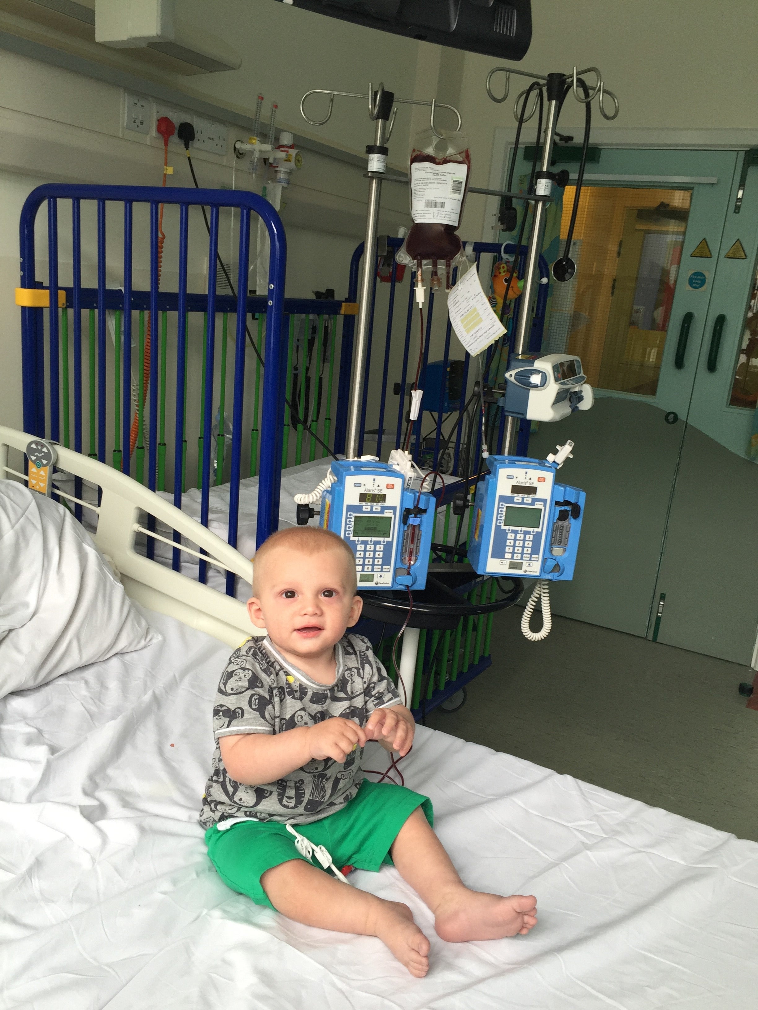 Alfie sitting on a hospital bed surrounded by machines 