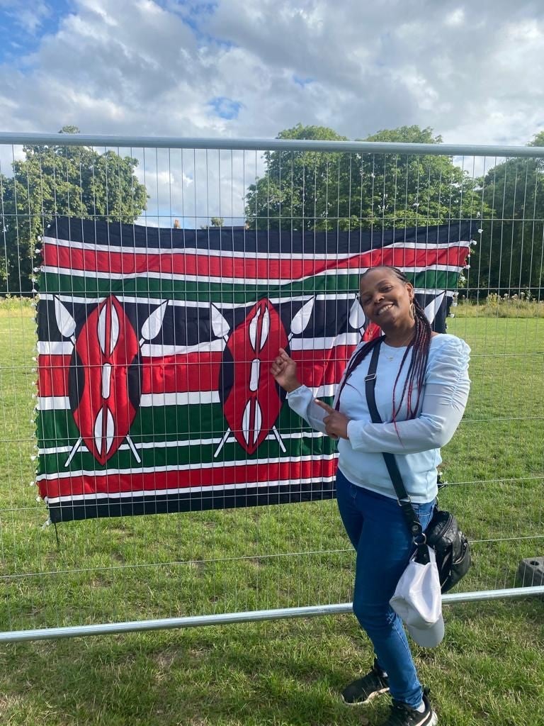 Purity standing in front of the Kenyan Flag