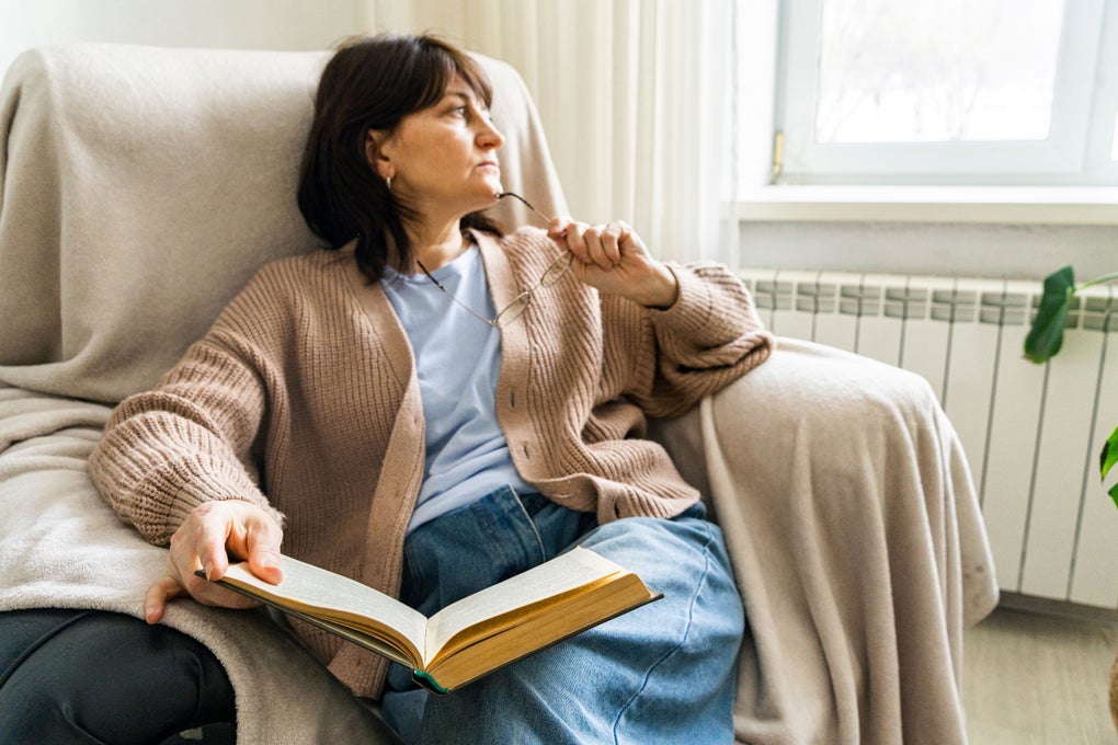 Woman with book sitting in armchair thinking about something and contemplating it