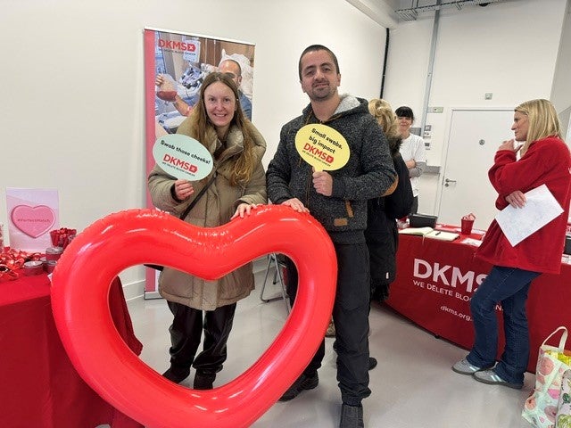 A man and a woman at a DKMS event holding a heart shaped balloon